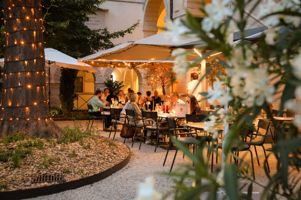 Dîner nocturne en terrasse illuminée sous les parasols du restaurant Epona à Lyon.