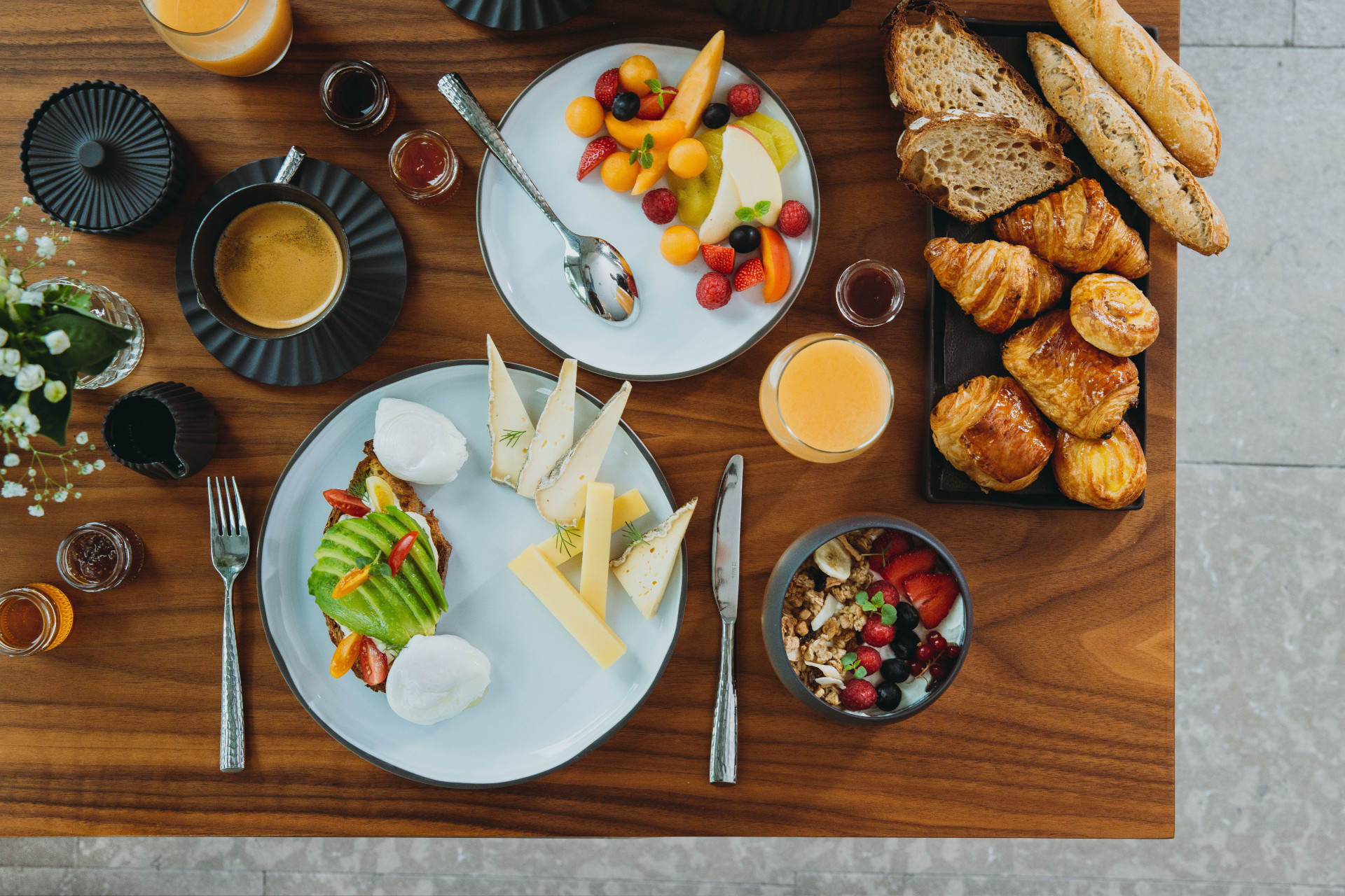 Buffet petit-déjeuner complet à Lyon avec tartines avocat, œufs pochés, viennoiseries et jus frais.